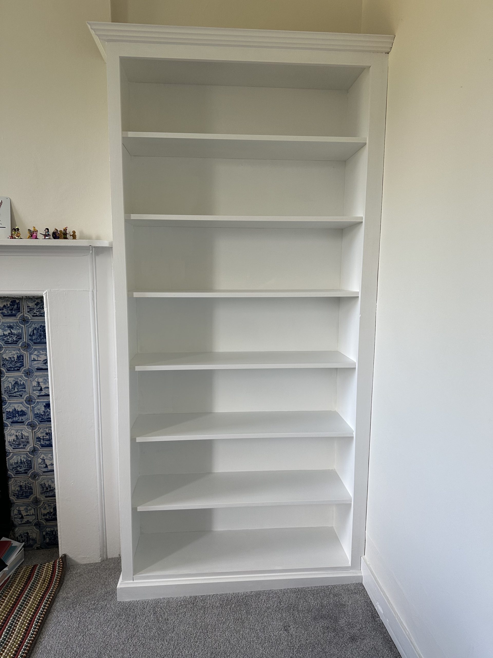 Large full height fitted bookcase with shelving for books and display items, painted in White.