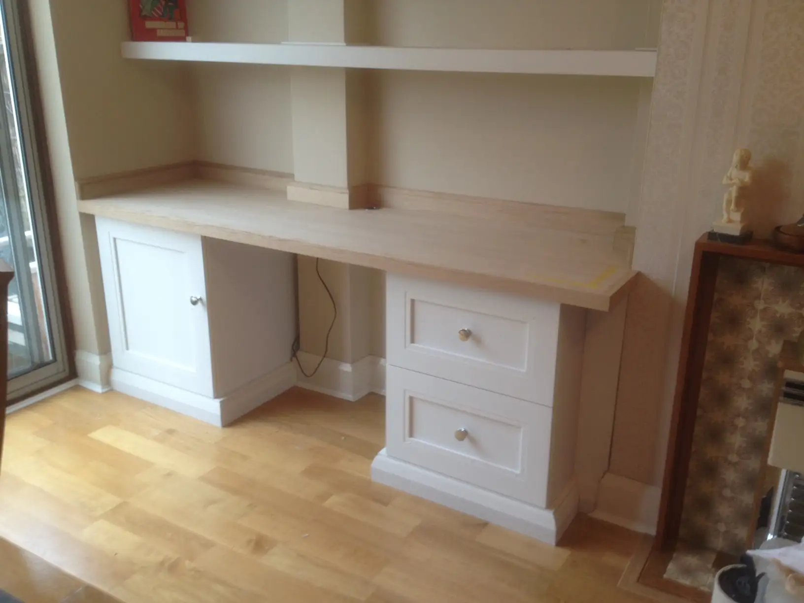 Bespoke built in cabinet and drawers with floating shelves above, and painted white.