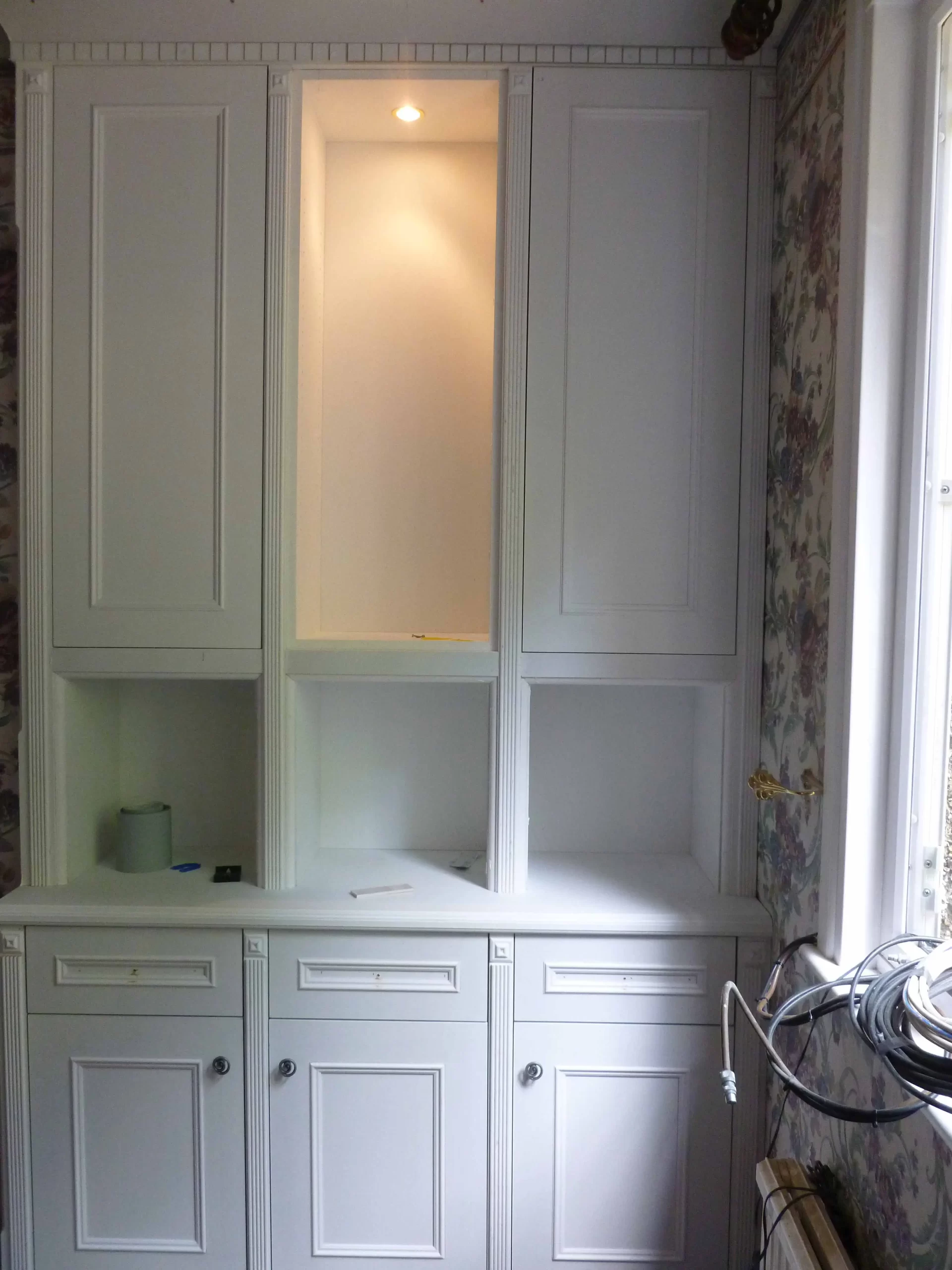Fitted alcove cabinet with shaker style doors, lighting and drawers painted in white.