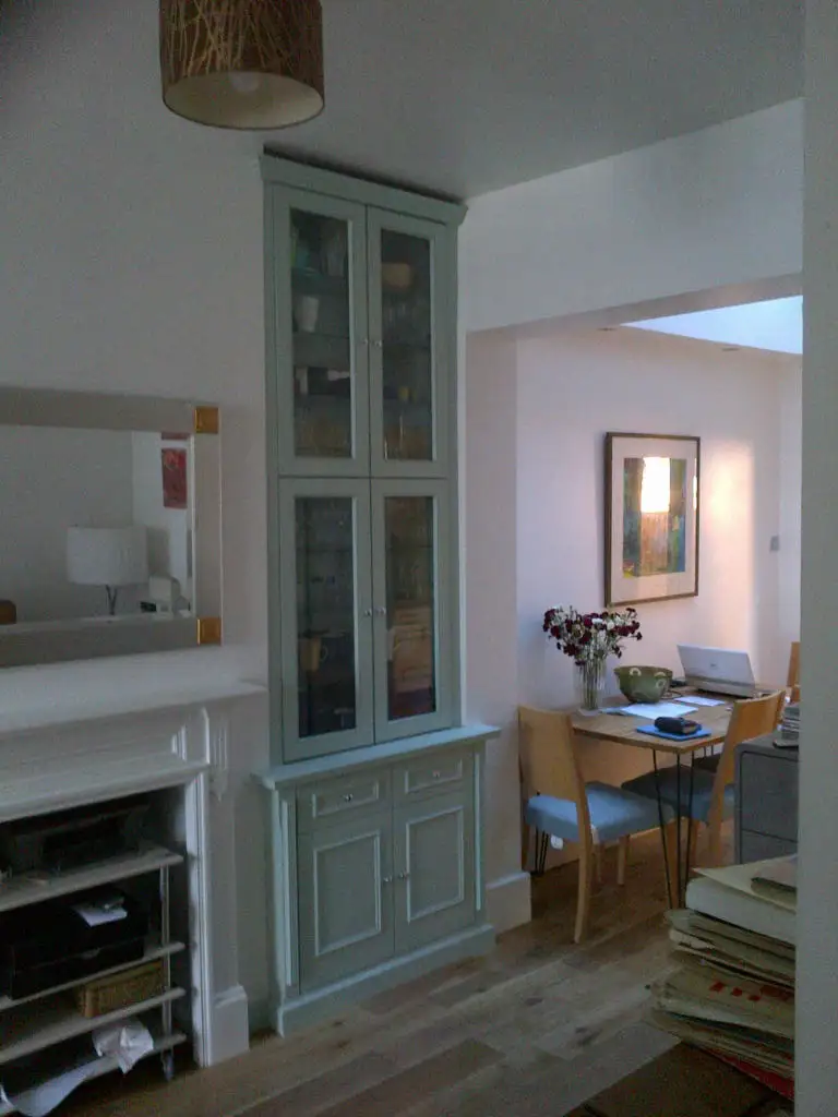 Fitted display cabinet with glass doors and glass shelves, painted in Farrow & Ball green.
