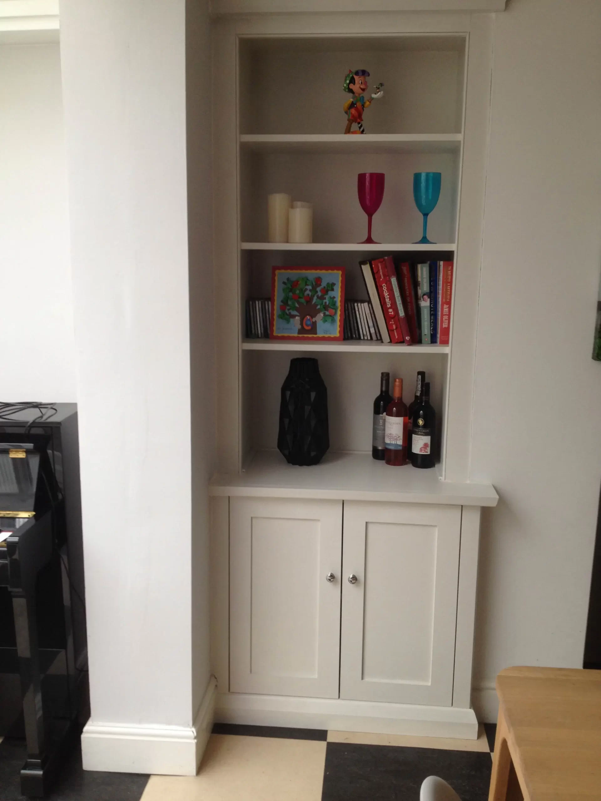 Fitted white cupboards with upper bookcase shelving.